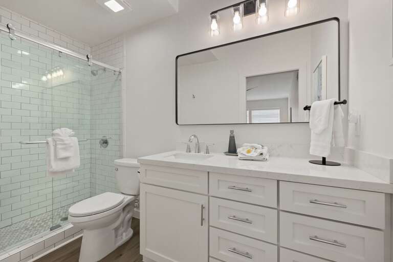 The guest suite's private bathroom features a spacious vanity and beautifully updated glass-enclosed shower.