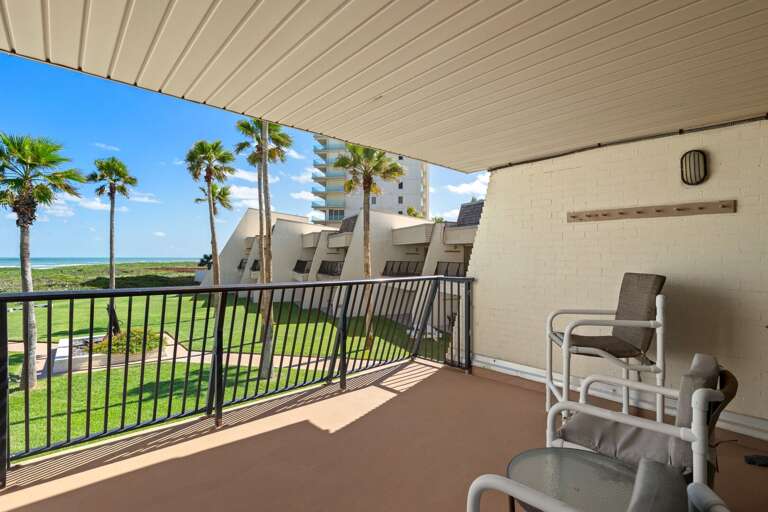The spacious covered balcony offers outdoor seating and beautiful views of the surrounding coastal scenery.