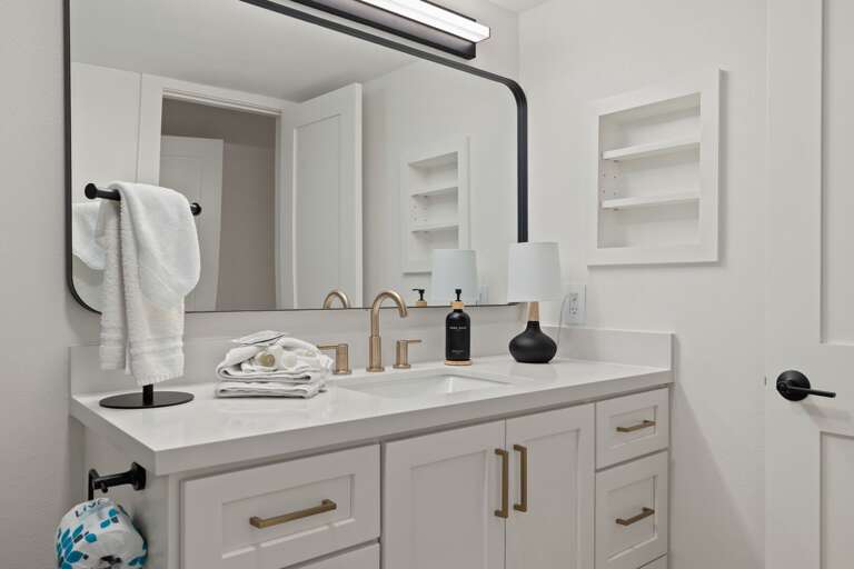 The primary bedroom's ensuite bathroom features a bright vanity, modern fixtures, and convenient counter space.