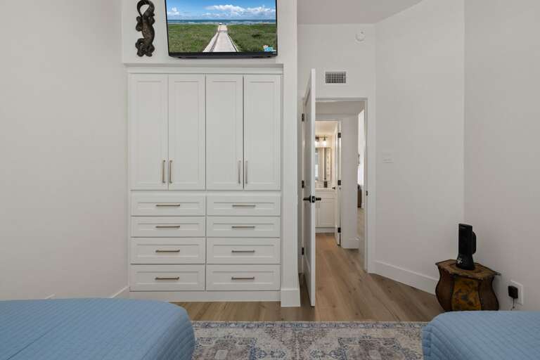 The twin guest bedroom offers two separate beds, a mounted TV, and convenient built-in storage.