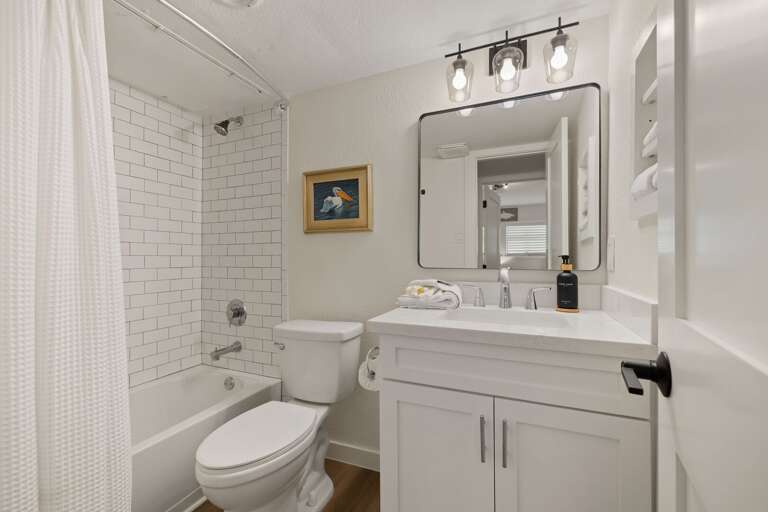 The shared guest bathroom features an updated vanity and a tiled shower and bathtub combination.