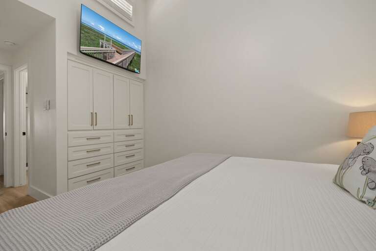 The king primary suite features a mounted TV, built-in storage, and convenient access to its private bathroom.