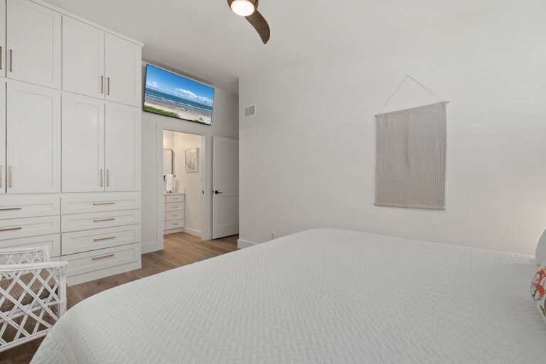The spacious guest suite features a comfortable king bed, mounted TV, and convenient built-in storage.