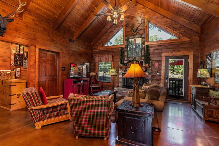 Rustic Interior Living Space With Wooden Walls And Ceiling, Furniture, And Chandelier