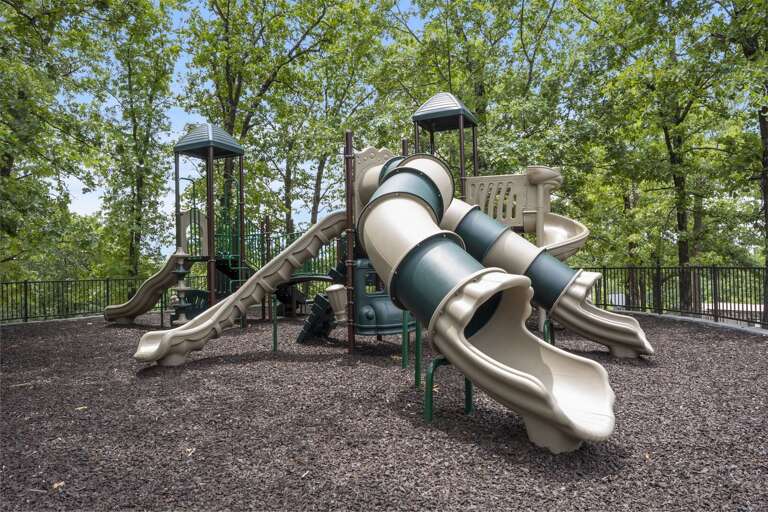 Playful Park Scene With Slide Set Nestled Neatly Beneath Trees