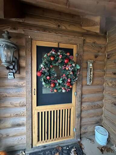 Wooden Cabin Entrance Adorned With A Decorative Floral Wreath