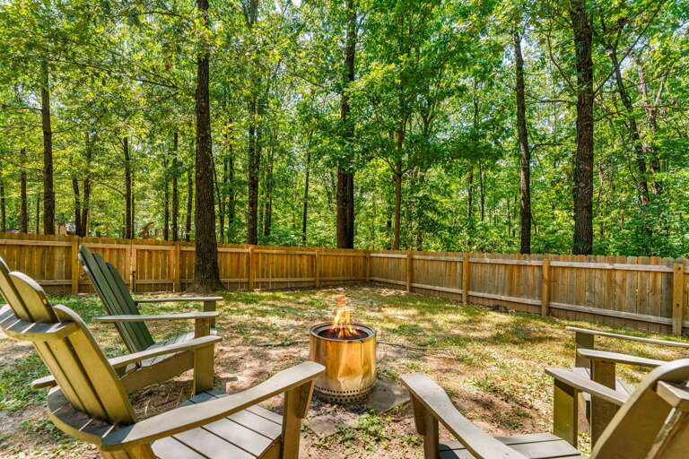Wooded Backyard At A Vacation Rental With Chairs Around A Fire Pit