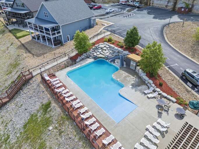 Aerial View Showing A Blue Pool Beside A Large Building, Lined With Lounge Chairs