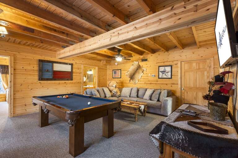 Wooden Interior Living Space With Pool Table, Sofa, And Mounted Animal Head