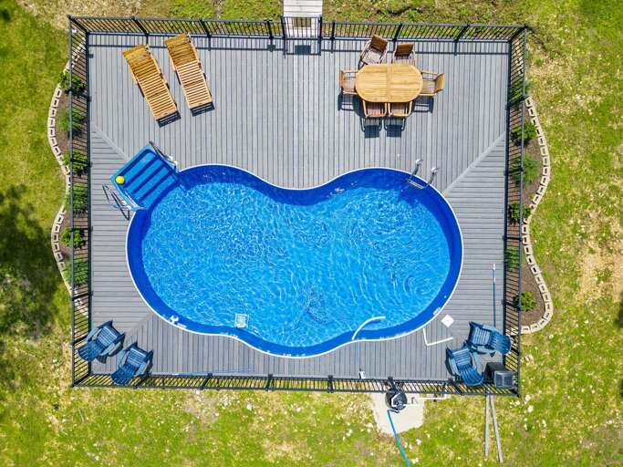 Aerial View Of A Kidney-shaped Swimming Pool With Surrounding Deck And Loungers Aerial View Of A Kidney-shaped Swimming Pool With Surrounding Deck And Loungers