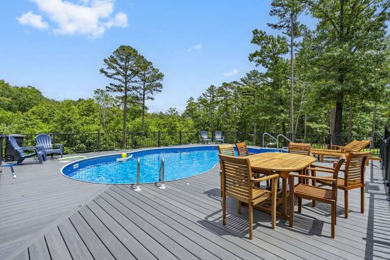 Outdoor Swimming Pool With Dining Furniture On Deck Surrounded By Trees