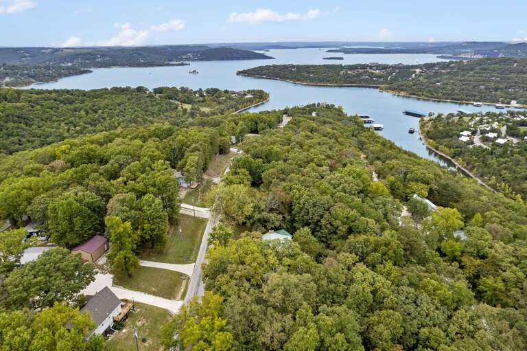 Aerial View Of A Lush Landscape By A Large Lake With Scattered Structures Aerial View Of A Lush Landscape By A Large Lake With Scattered Structures