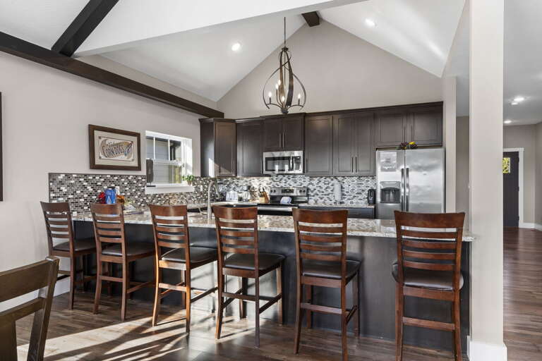 Spacious Kitchen With Bar Stools, Wooden Floors, And Pendant Lighting Spacious Kitchen With Bar Stools, Wooden Floors, And Pendant Lighting