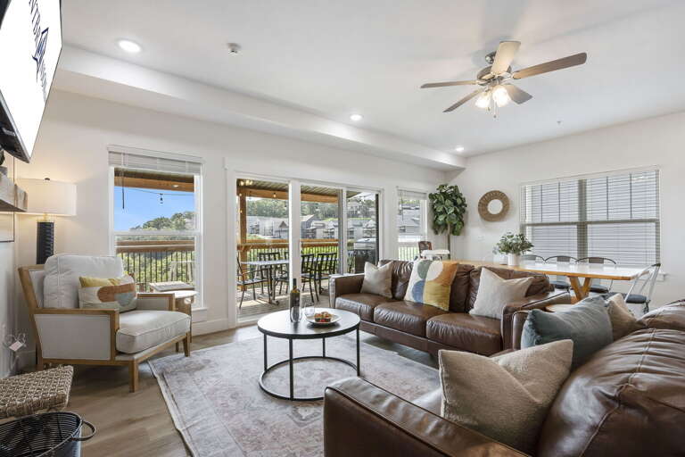 Living Room With Sectional Sofa, Armchair, Ceiling Fan, And Balcony Access