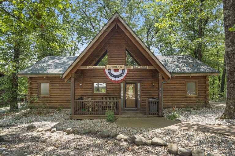 Rustic Cabin Surrounded By Trees With American Flag Decoration