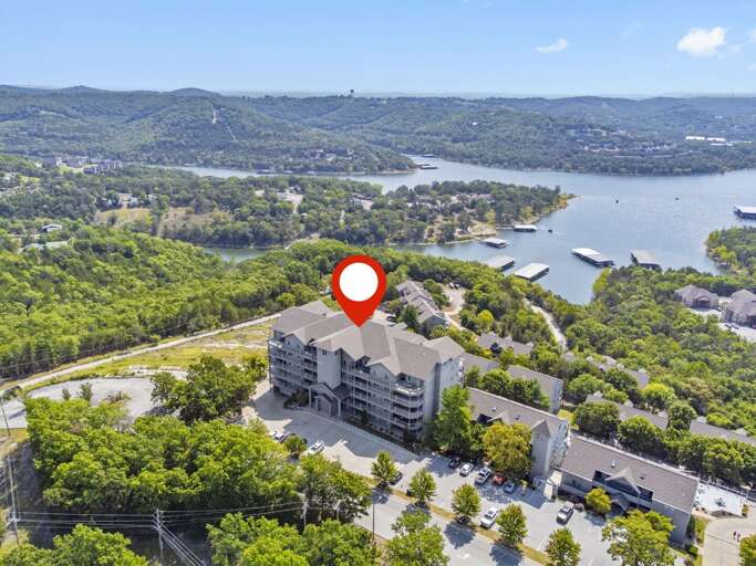Aerial View Of A Large Building Near A Lake With Lush Landscape