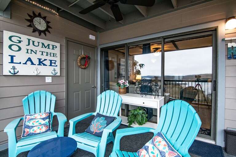 Balcony With Two Blue Chairs, Decorative Signs, And Lake View