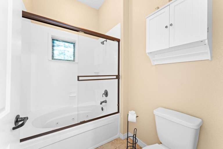 Bright Bathroom With Beige Walls, White Cabinet, And Bathtub
