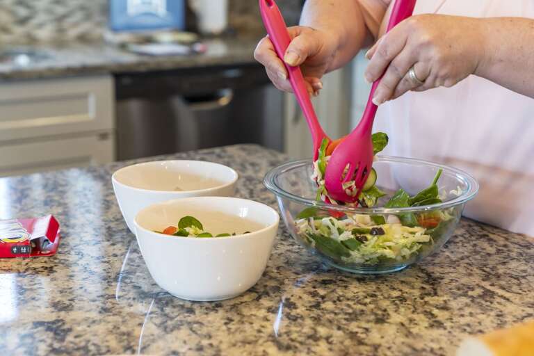 Person Preparing Salad In Vacation Rental Kitchen Person Preparing Salad In Vacation Rental Kitchen