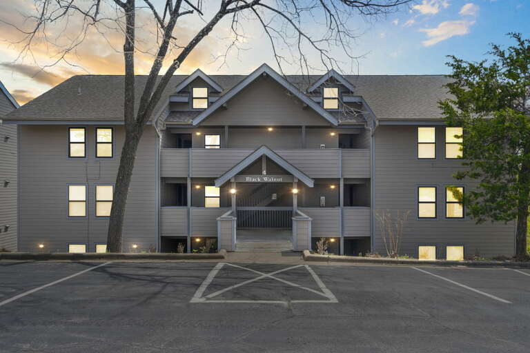 Three-story Residential Building With Parking Lot At Twilight