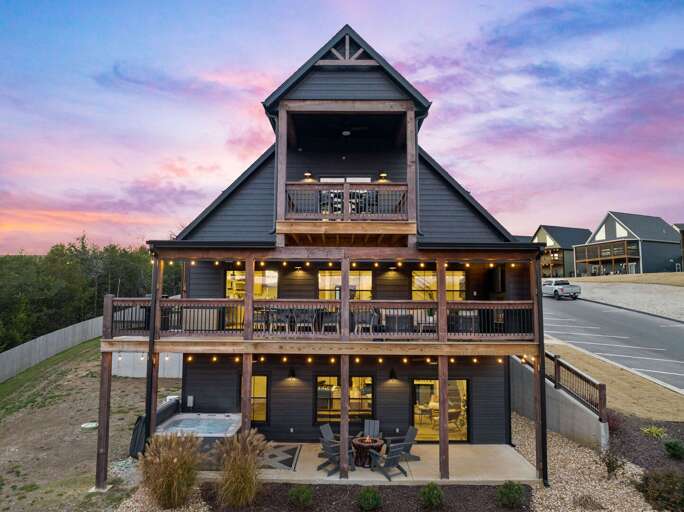 Three-story Building At Dusk With Multiple Balconies And Outdoor Lighting
