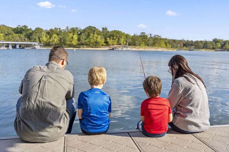 Family Fishing By A Lake On A Sunny Day