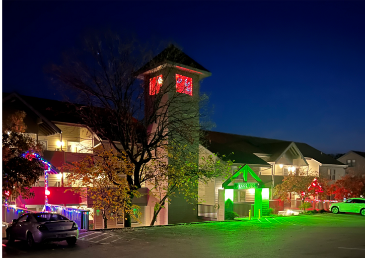 Nighttime View Of A Building With Neon-lit Entrance And Tower, Cars Parked Nighttime View Of A Building With Neon-lit Entrance And Tower, Cars Parked