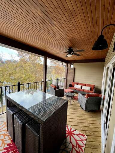 Screened Porch With Plush Seating And Paneled Ceiling, Overlooking Lush Landscape