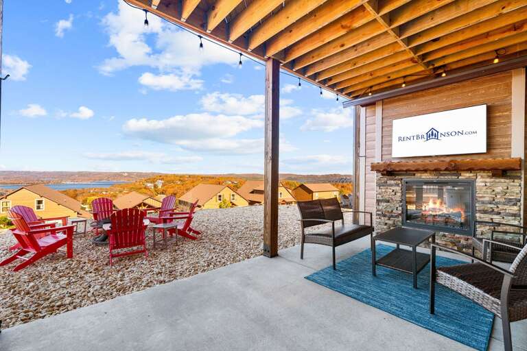 Wood-beamed Balcony With Red Chairs Overlooking Lakeside Settlement, Stone Fireplace Lit