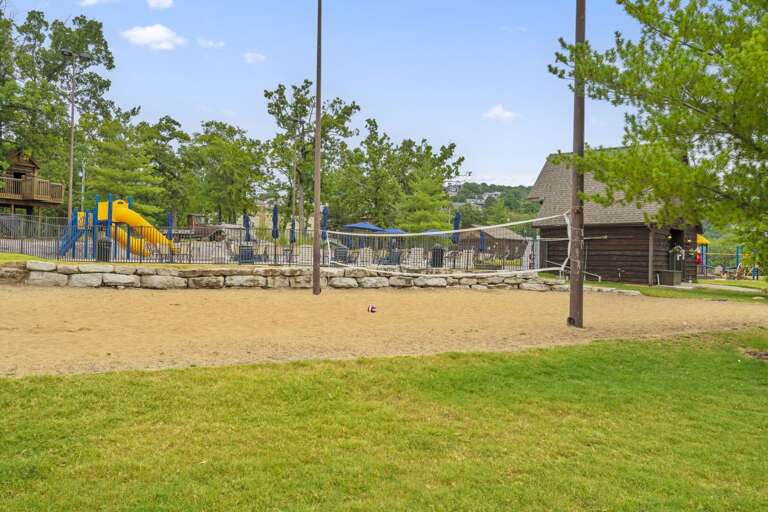 Park Playground And Sandy Volleyball Court Beneath Broad Blue Sky