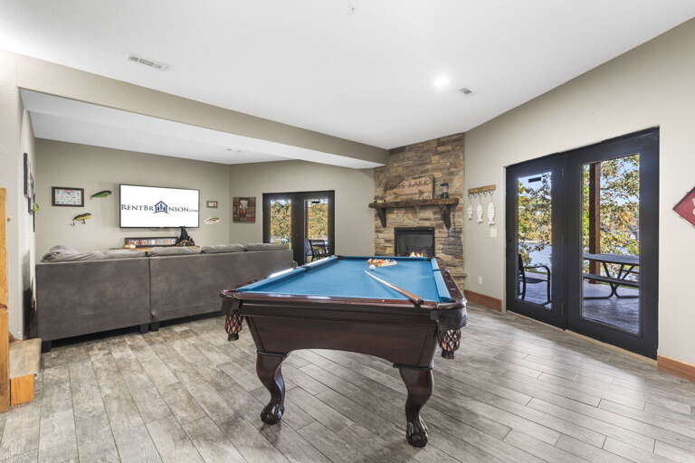 Interior Room With Billiards Table, Stone Fireplace, And Double Doors Leading Outside