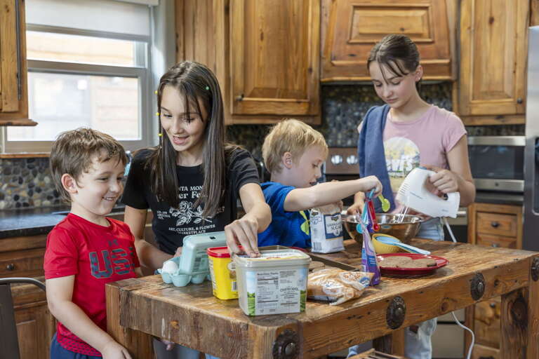 Family Baking Together In A Rustic Kitchen