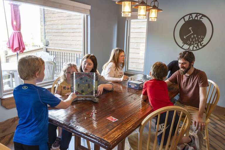 Family Enjoying Game Time Together In A Vacation Rental Dining Room Family Enjoying Game Time Together In A Vacation Rental Dining Room