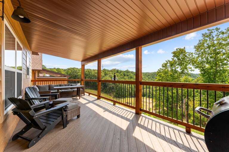Wood-lined Porch With Chairs And Grill Overlooking Green Landscape