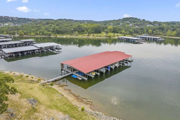 Aerial View Of A Large Marina With Red-roofed Docks Nestled Near A Green Shoreline Aerial View Of A Large Marina With Red-roofed Docks Nestled Near A Green Shoreline