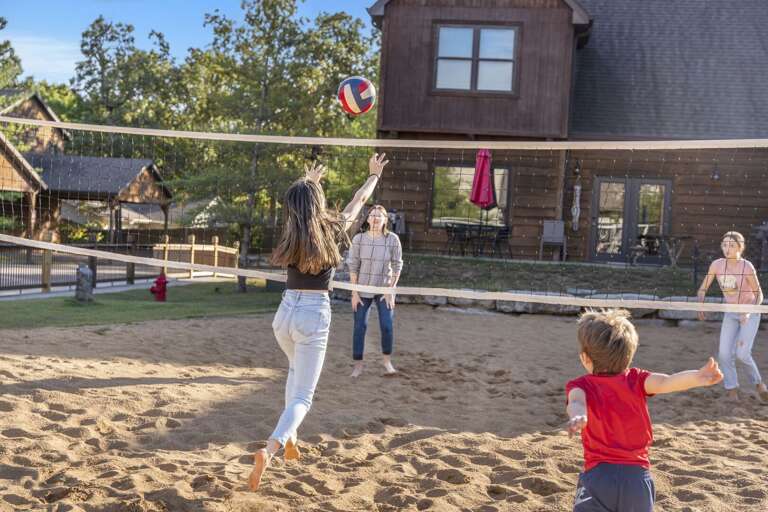 Family Playing Volleyball Near Brown Building On Sandy Court