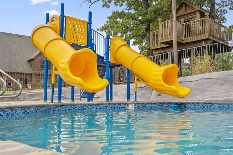 Blue Pool With Bright Yellow Slides Beside Beige Buildings
