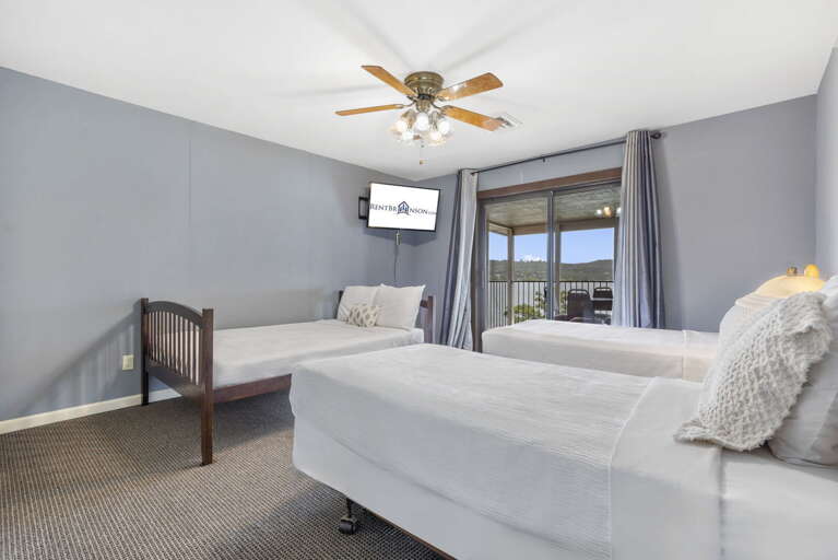 Simple Sleeping Space With Twin Beds, Ceiling Fan, And Balcony Access