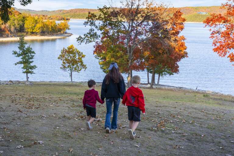 Family Walking Toward Water With Autumnal Trees