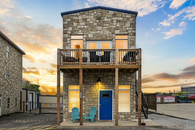 Two-story Stone Building With Balcony And Blue Door At Dusk Two-story Stone Building With Balcony And Blue Door At Dusk