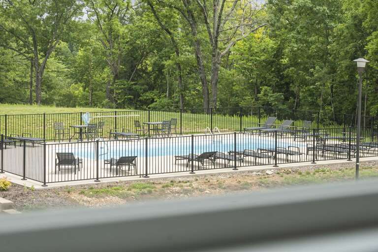 Swimming Pool With Loungers Behind Fence In Green Area