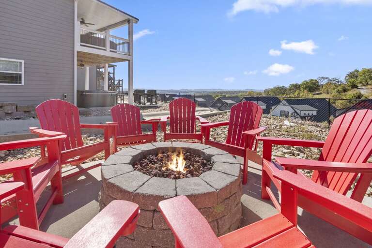 Red Chairs Circled Around A Flaming Fire Pit, Outdoor Setting With Clear Skies