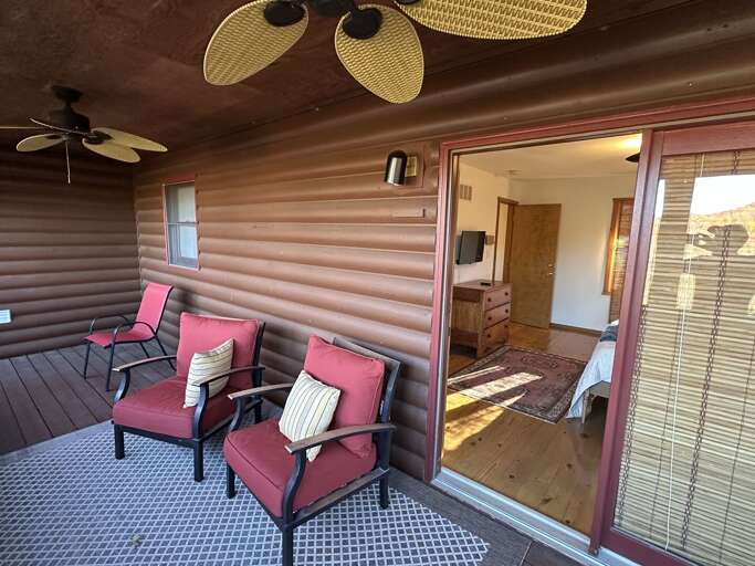 Vacation Rental Veranda With Vivid Chairs, Wooden Walls, And Ceiling Fans