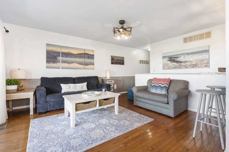 Living Room With Light Walls, Wooden Floor, Gray Sofas, And Landscape Paintings