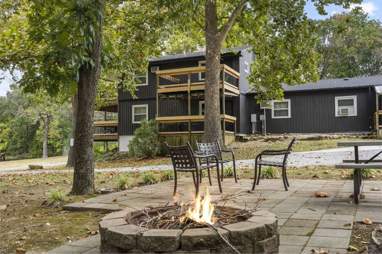 Black Building Bordered By Trees With A Blazing Fire Pit In Front Black Building Bordered By Trees With A Blazing Fire Pit In Front