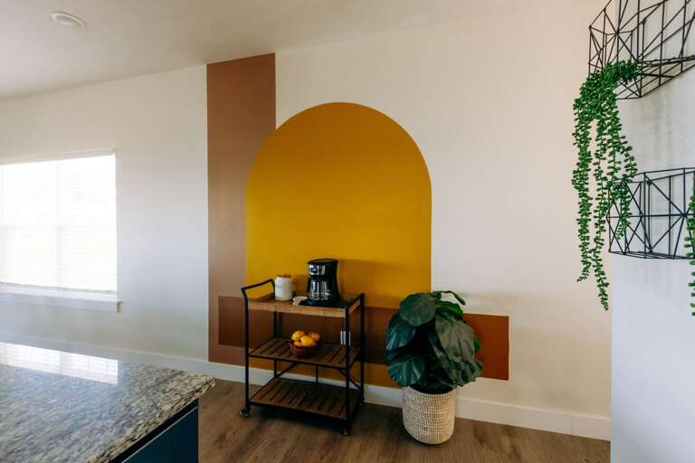 Bright Yellow Arch, Brown Shelves, Hanging Plant, And Potted Palm In Sunny Space