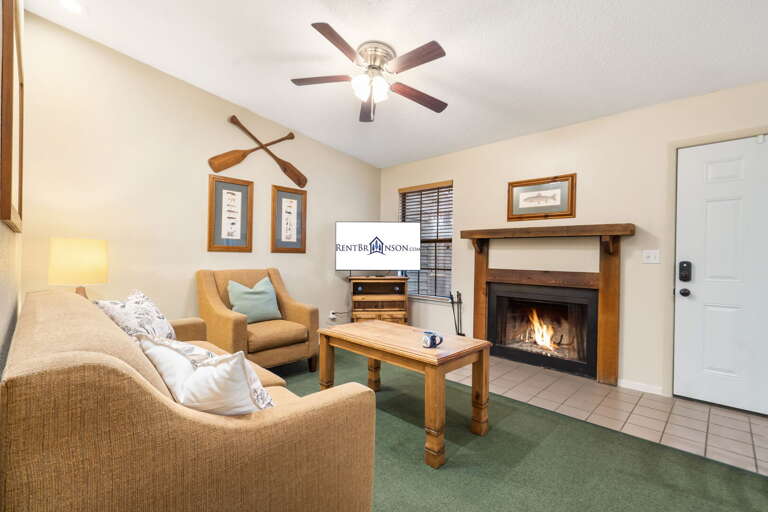 Living Room With Lit Fireplace, Furniture, And Ceiling Fan Living Room With Lit Fireplace, Furniture, And Ceiling Fan