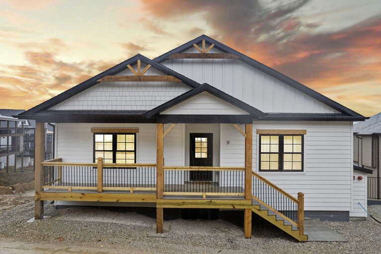 Sunset Skies Behind A Suburban Bungalow With Bright Windows And Wooden Walkway Sunset Skies Behind A Suburban Bungalow With Bright Windows And Wooden Walkway