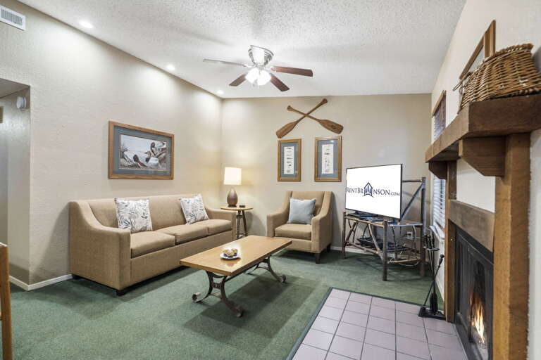Living Area With Tan Sofas, Tiled Fireplace, And Mounted TV
