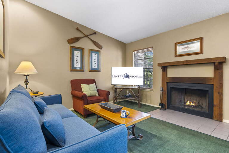 Furnished Living Space With Fireplace, Framed Photographs, And Blue Sofa